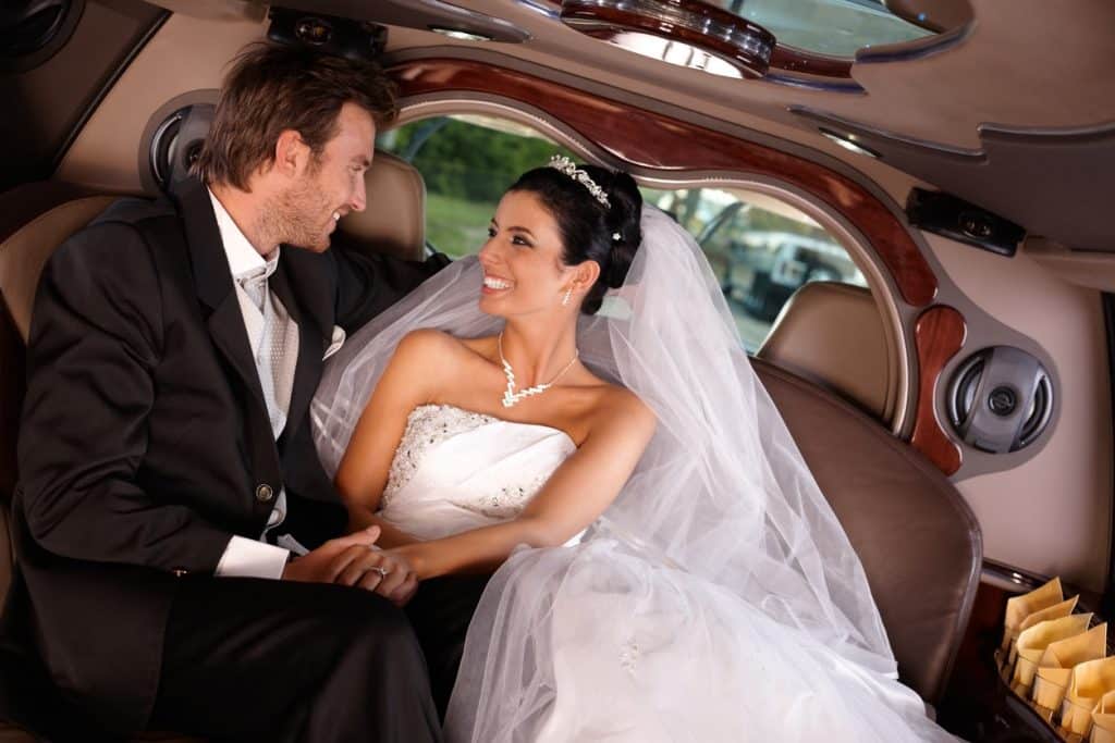 Happy young couple sitting in limousine on wedding day.