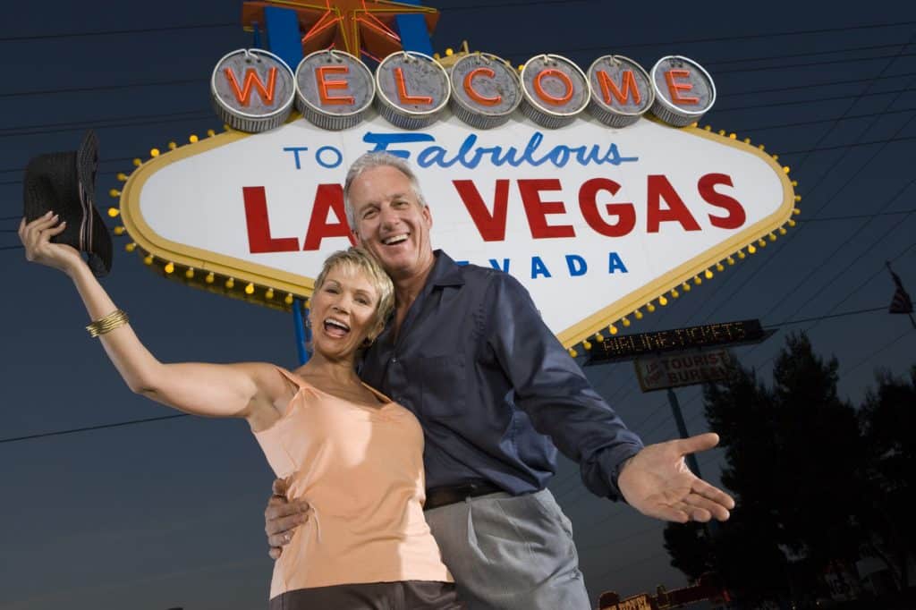 Portrait of middle-aged couple in front of Welcome to Las Vegas sign, low angle view