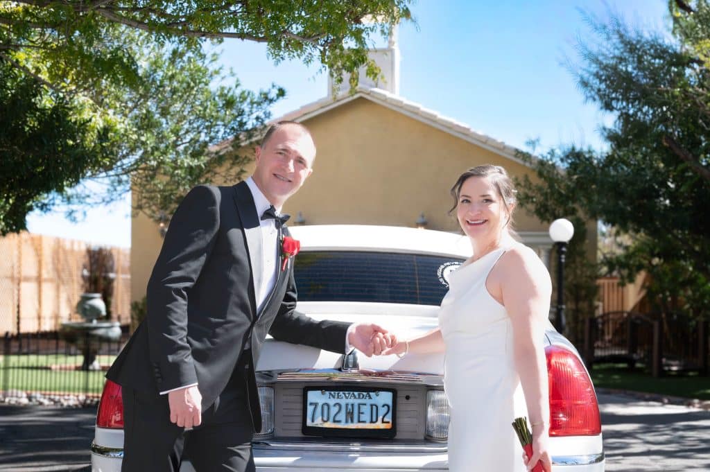 Bride and Groom posing together next to elegant limo at Mon Bel Ami Wedding Chapel in downtown Las Vegas.